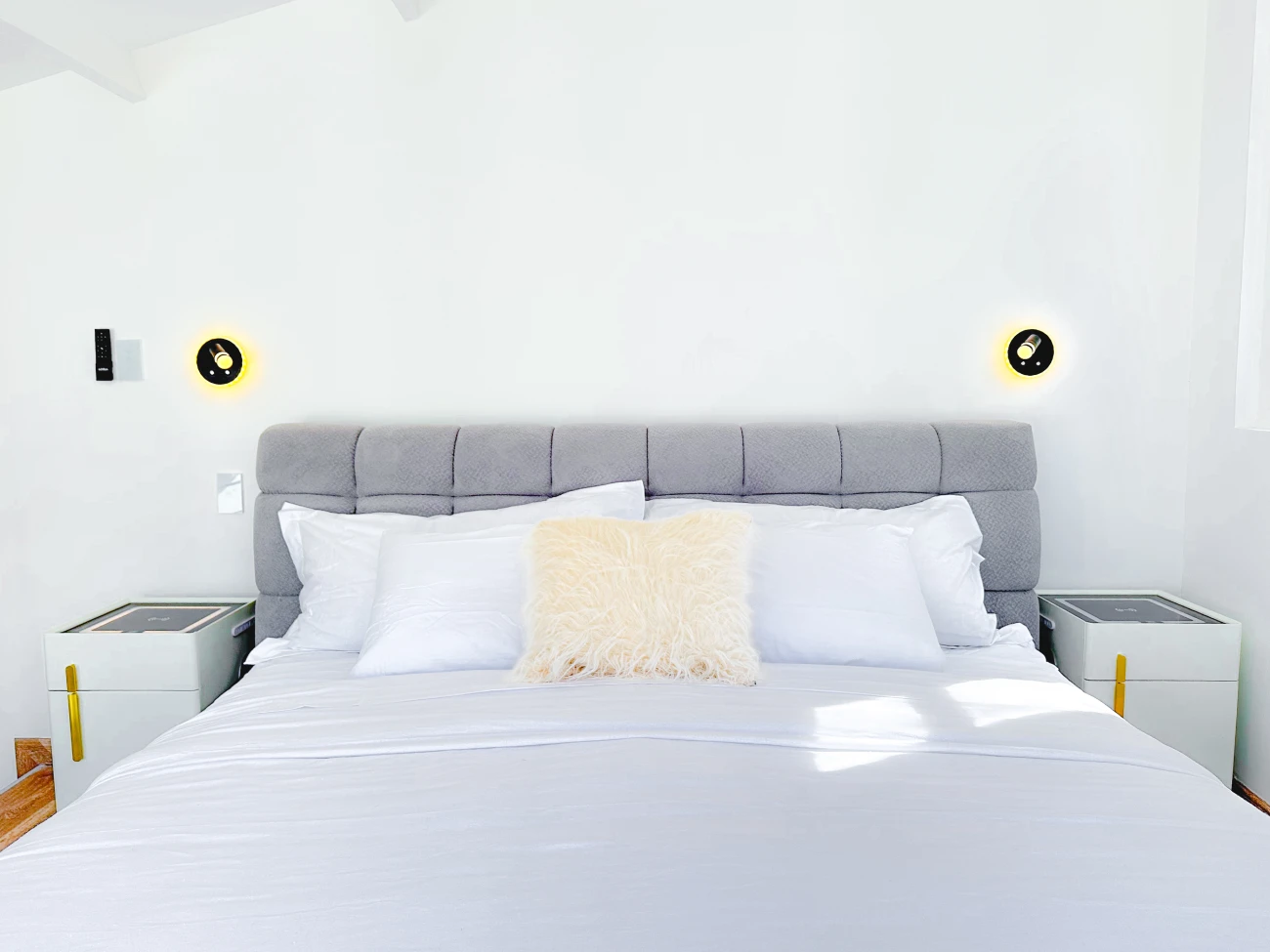 Modern bed with a grey tufted headboard and a fluffy pillow.