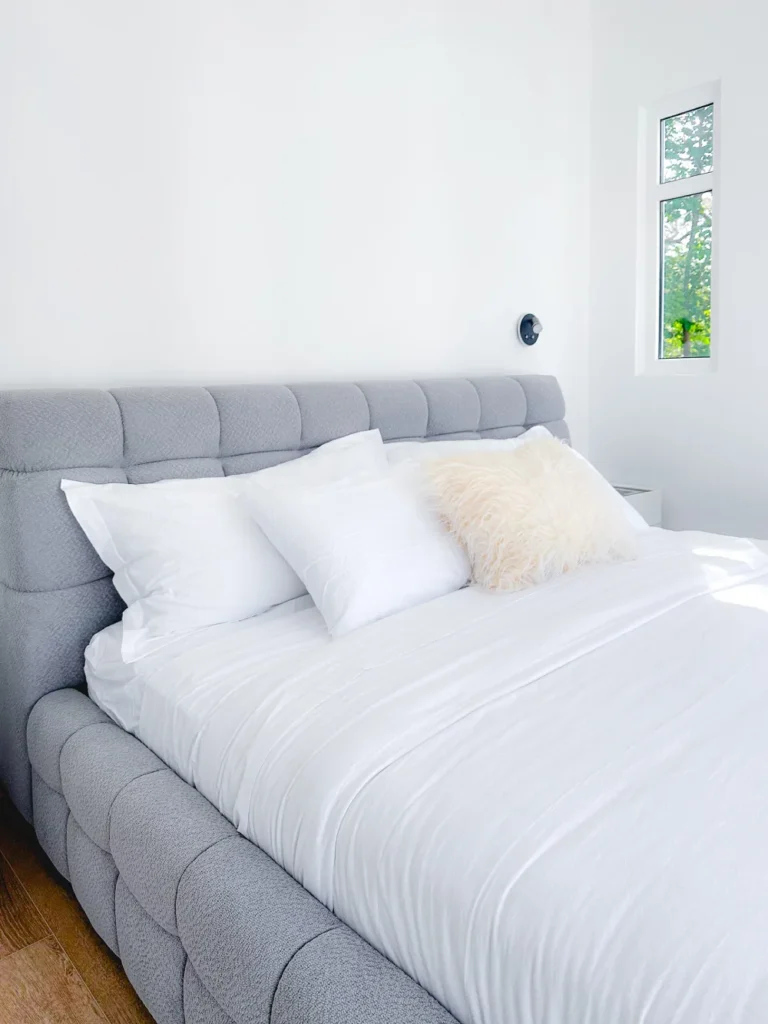 Bed dressed with high-quality white linens and luxury pillows offering superior comfort.