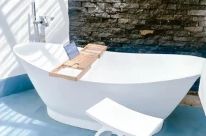 Designer standalone tub with an organizer caddy, ideal for enjoying a book or a drink during your rest.