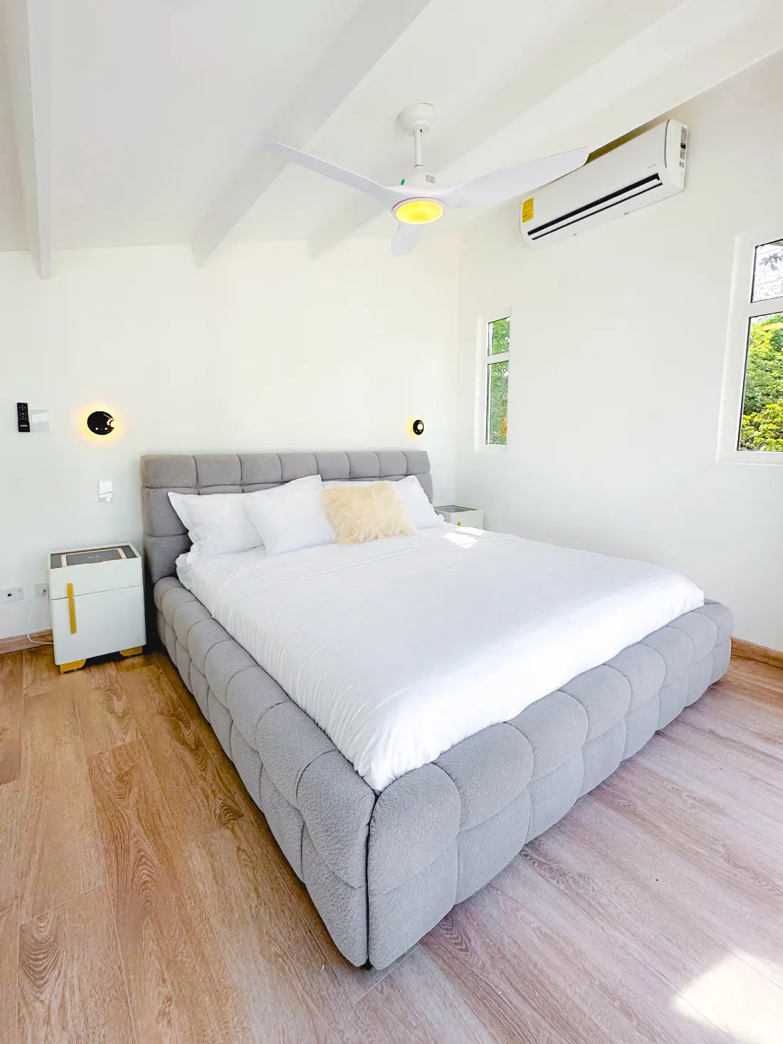Modern bedroom with a quilted gray King-size bed, white ceiling fan, and air conditioning.