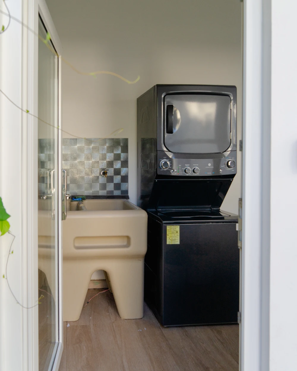 Laundry area equipped with a modern washer-dryer unit and utility sink in a pristine setting.