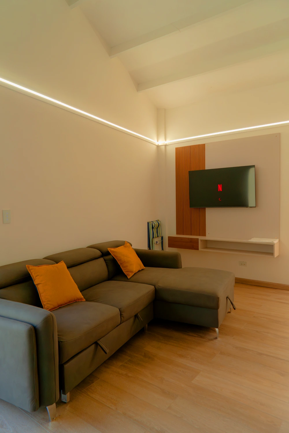 Modern living area with a convertible sofa bed and a wall-mounted Smart TV.
