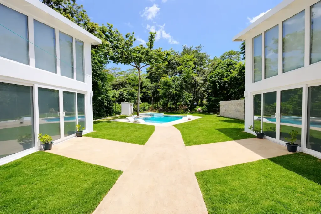 T Loft pool entrance with modern two-story buildings flanking central courtyard and pristine garden
