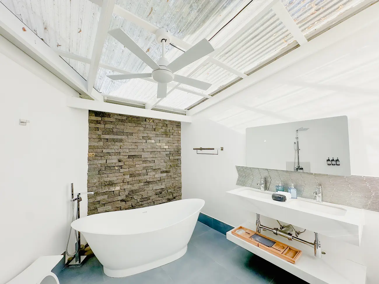 Two wall-mounted white vanities with integrated sinks and a five-blade white ceiling fan in a modern bathroom.